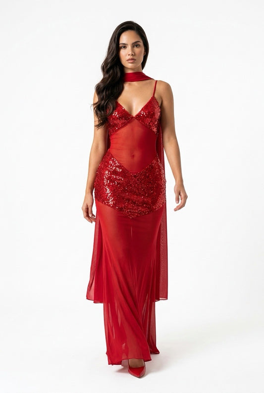 A woman modeling a red evening gown with a sheer mesh bodice, sequined waist, and flowing skirt against a plain white studio background.