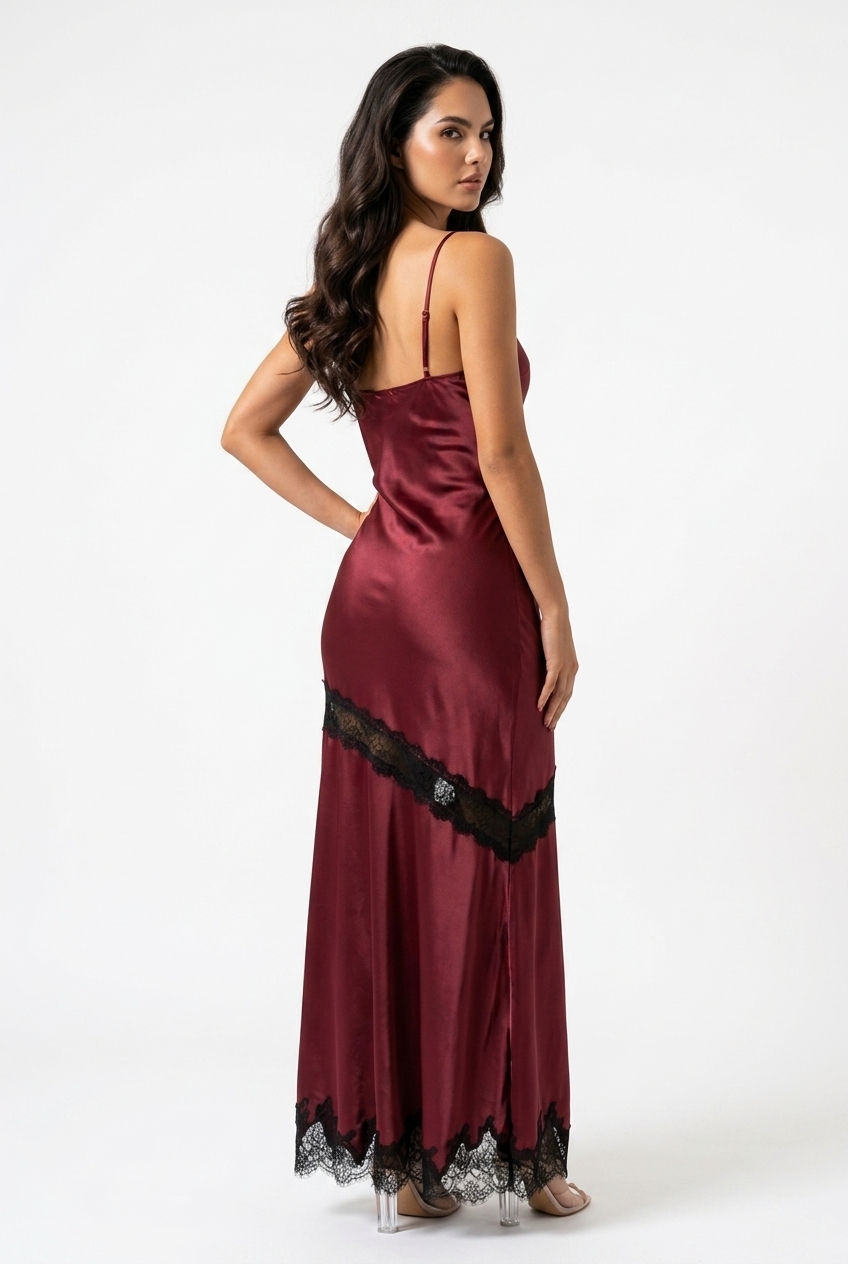 A woman modeling a burgundy satin slip gown with black lace trim, shown from the back against a plain white studio background.