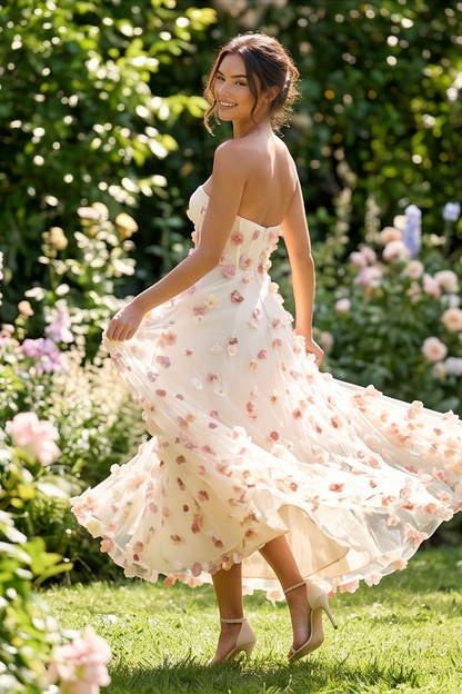 Woman in a floral dress standing in a garden with flowers and greenery around her.