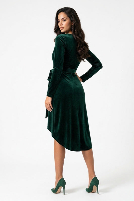 A woman modeling a dark green velvet long-sleeve wrap dress with a tie waist, shown from a three-quarter back angle against a plain white studio background.