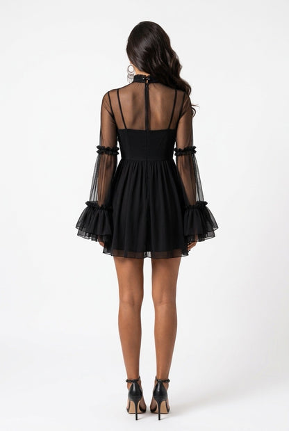 A woman viewed from the back wearing a black mini dress with sheer long sleeves, a high neck, and a ruffled hem, paired with black high heels against a plain white studio background.