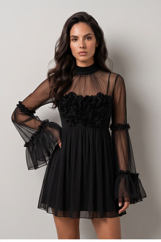 A woman modeling a black sheer mesh mini dress with a ruffled floral bodice, high neck, and flared bell sleeves with ruffled cuffs, against a plain light gray studio background.