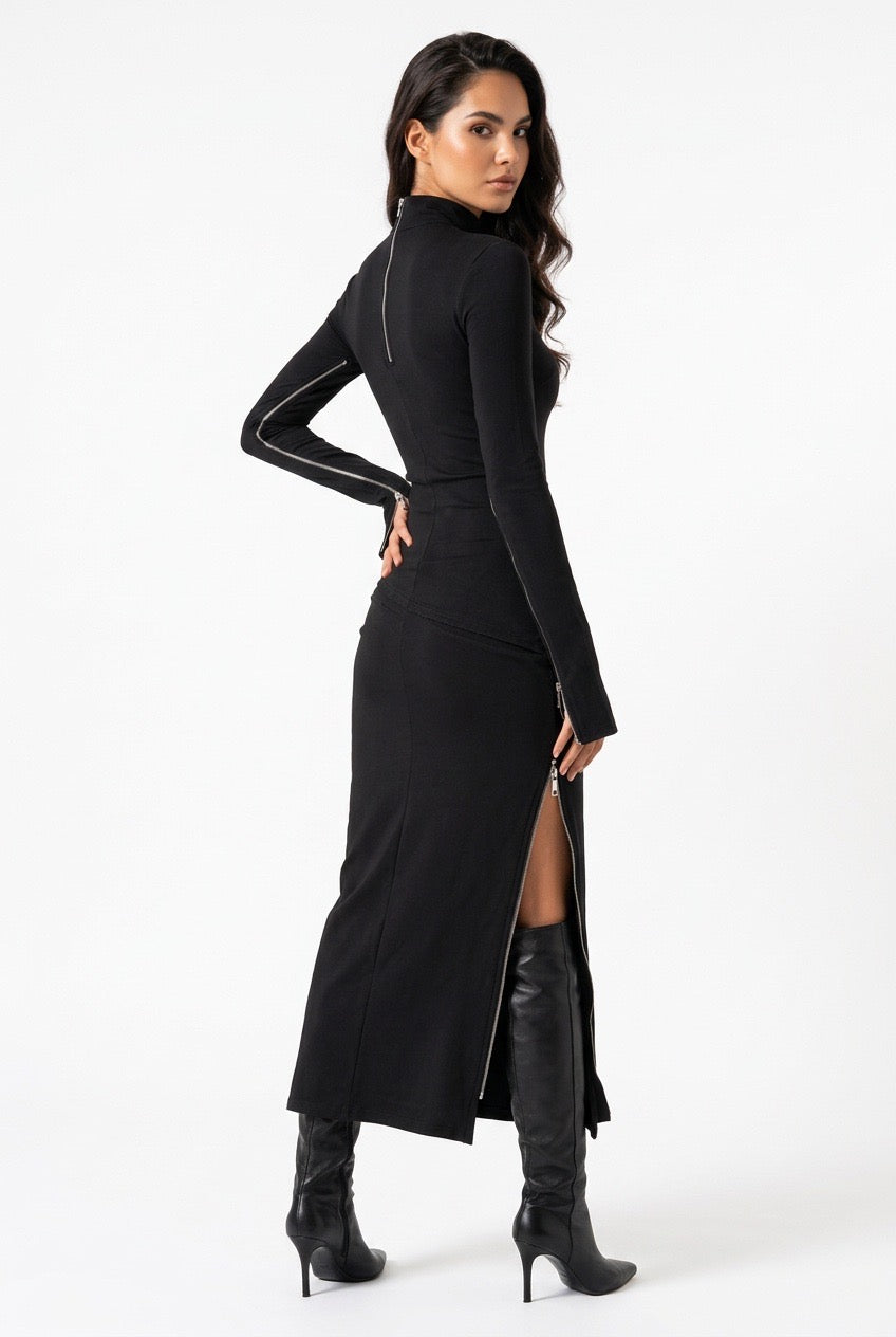 A woman modeling a black long-sleeve mock-neck midi dress with a high thigh slit, shown from a three-quarter back angle against a plain white studio background.
