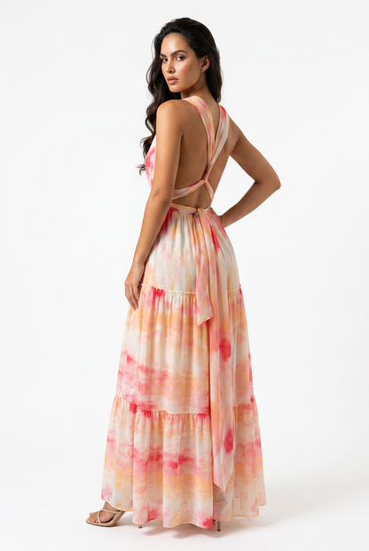 Model wearing the Sunset Tie-Dye Maxi Dress featuring a tiered silhouette, halter neckline, and open-back tie detail in a vibrant tie-dye print.-side view