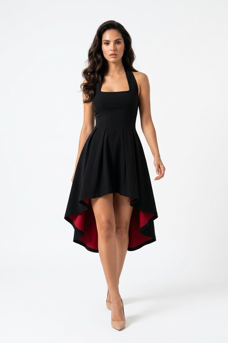 A woman modeling a black halter-neck swing dress with a high-low hem and a contrasting red lining, set against a plain white studio background.