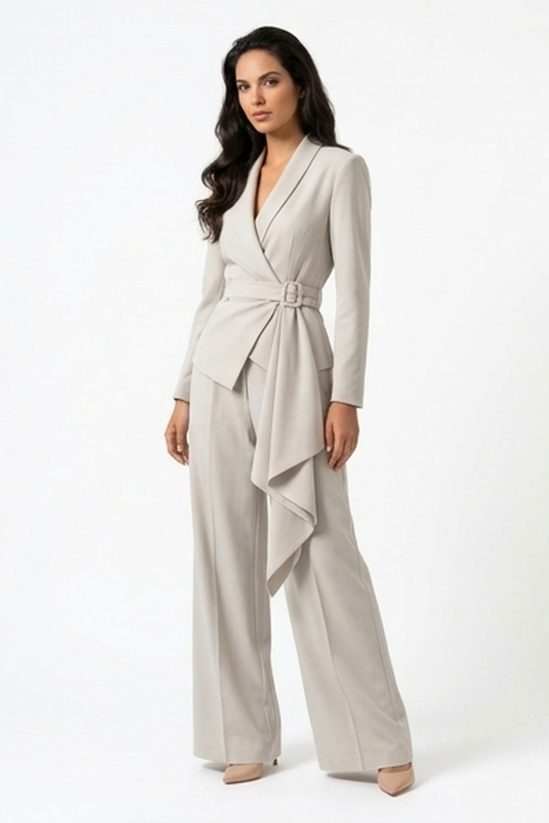 A woman modeling a light beige wrap-style jumpsuit with long sleeves, wide legs, and a belted waist, photographed against a clean white studio background.