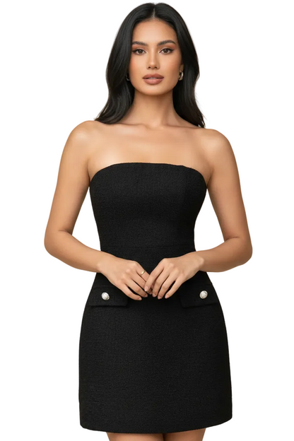 Woman wearing a black strapless dress with white buttons on a beige background